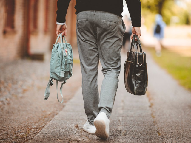Person walking outside carrying two bags